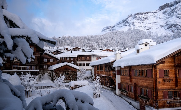 snow covered buildings in front of a snowy mountainside