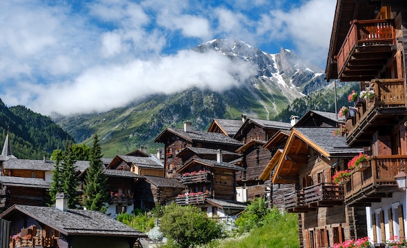 wooden buildings with swiss mountains visible in the background